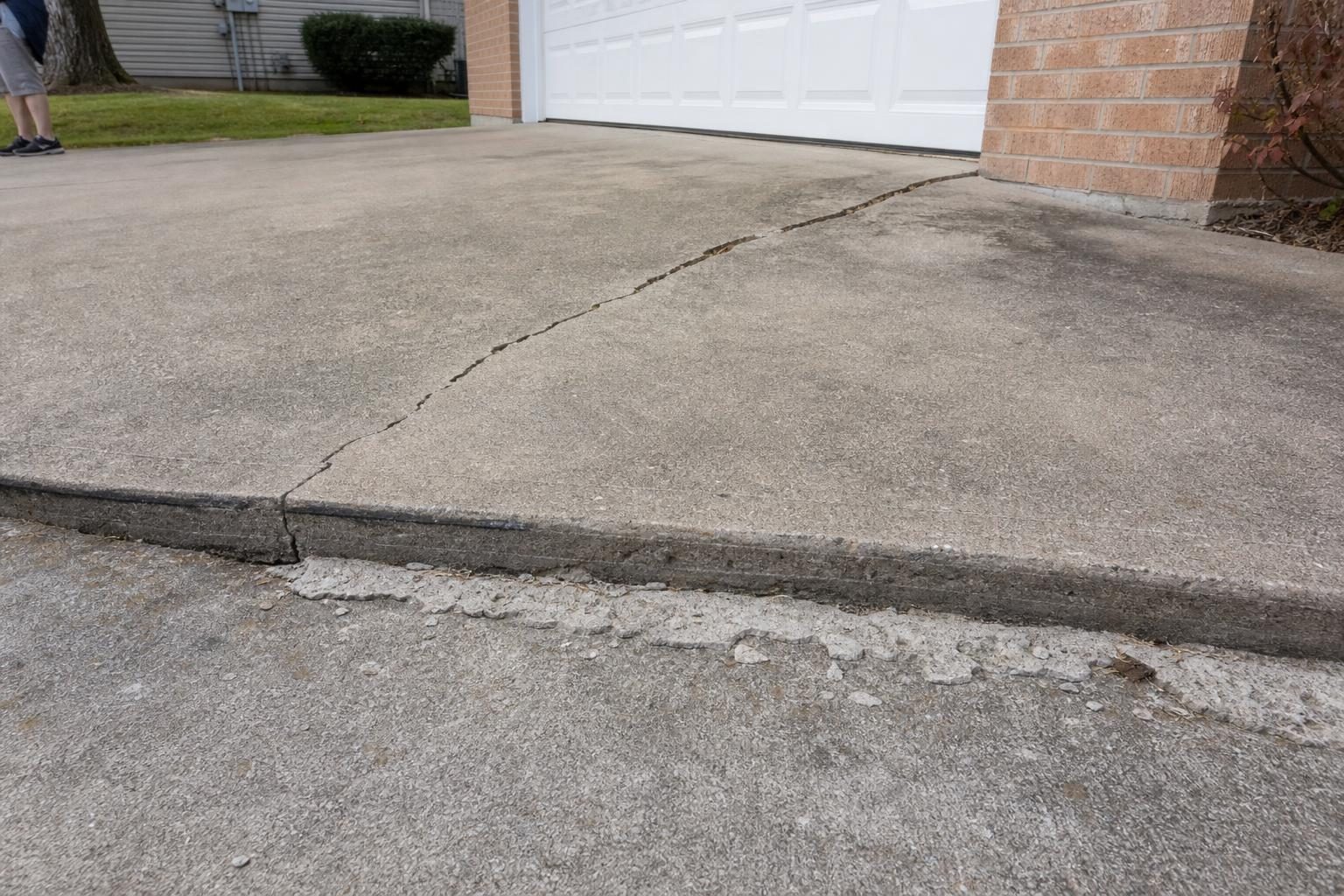 A widening crack, an uneven slab edge and surface flaking are signs a concrete driveway needs attention.